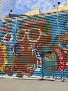 Corrugated metal siding at construction site with large mural depicting a person and sayings like I love hip-hop and follow your heart.