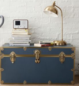 Blue trunk from Pottery Barn teen serving as a side table in a cool space with an old brick wall.