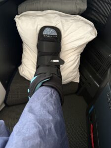 On the airplane with my fractured foot propped up and wearing my boot.